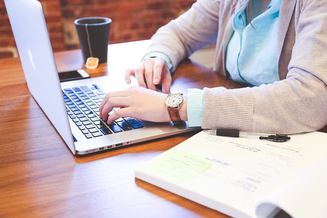woman working on her computer with a book and a glass of tea