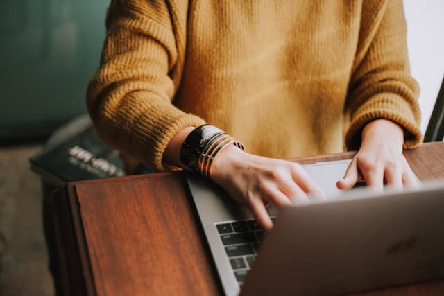 person working on her computer in a while blouse