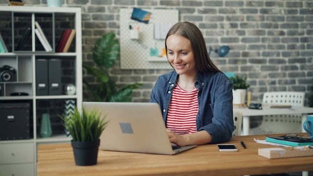 girl working and smiling on her computer